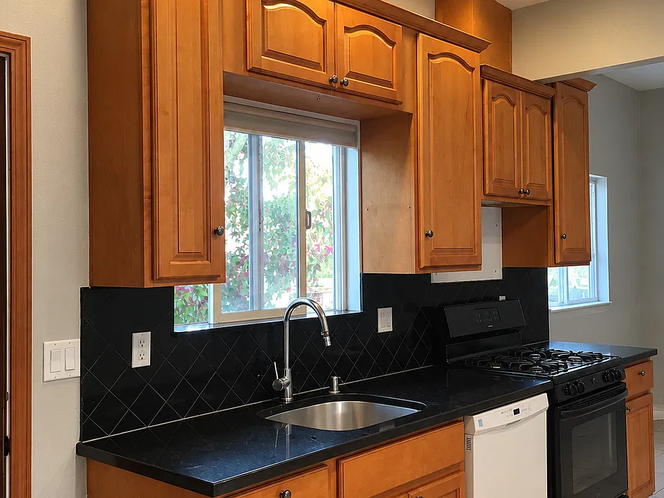 Open-space kitchen includes solid wood cabinet, gas stove, garbage disposal, and dishwasher.