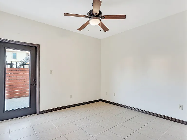 Unoccupied room in Merida Vista Apartments, with a ceiling fan and a door, situated in Laredo, Texas