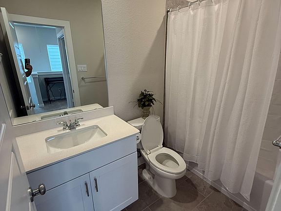 Full bathroom with a wide vanity and sink, framed mirror, and a shower/tub combo with curtain for easy daily use.