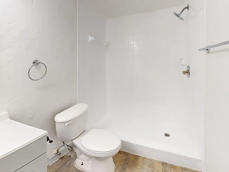 Modern, spacious bathroom featuring sleek white tiles, a walk-in shower, and contemporary fixtures.