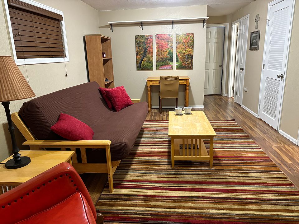 Living room: mission style furniture, couch/full futon (if needed), workspace, bookshelves. 5 doors along R wall: Entry, kitchen (not shown), laundry room, linen closet, bathroom. 2 windows on left wall with window film & custom blinds for privacy.