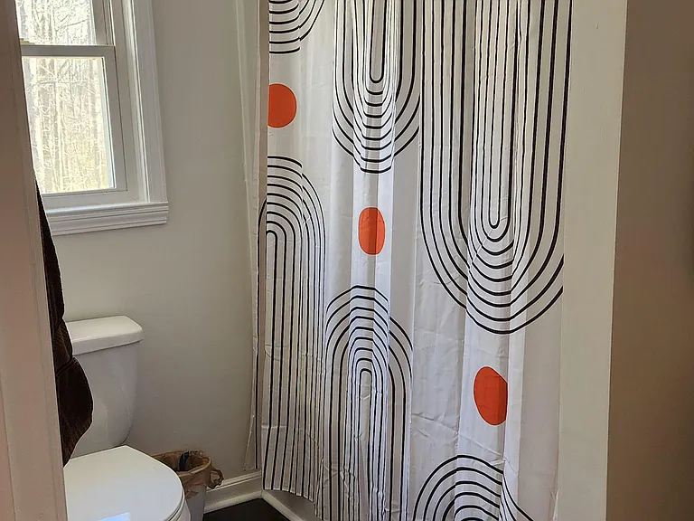 Full bathroom with a tub/shower combo, window for natural light, and durable flooring for easy upkeep.