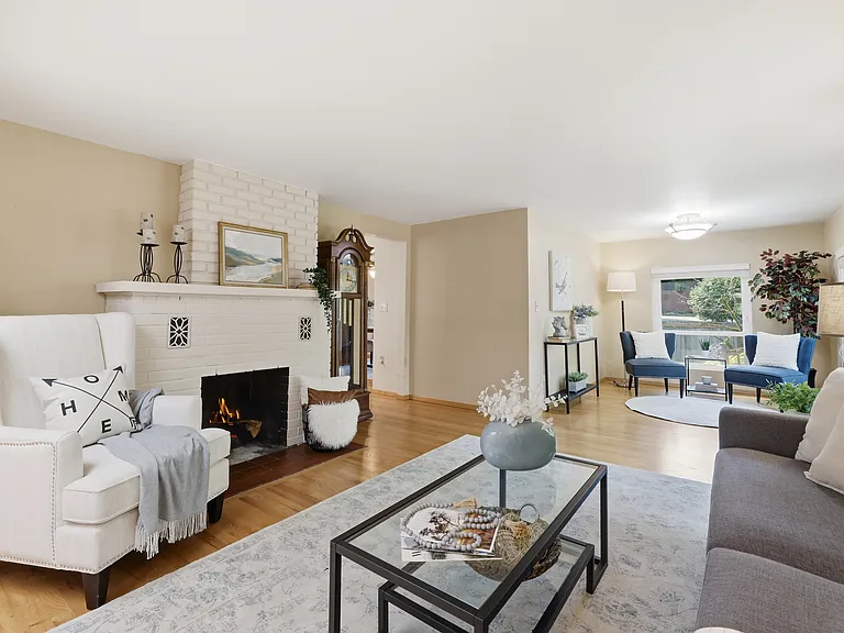 Bright living room with white-brick wood-burning fireplace and refinished hardwood floors