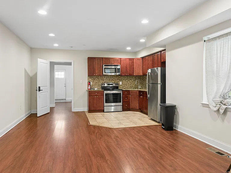 Open kitchen with ample cabinetry, tile backsplash, and stainless-steel appliances, flowing into a spacious dining area.