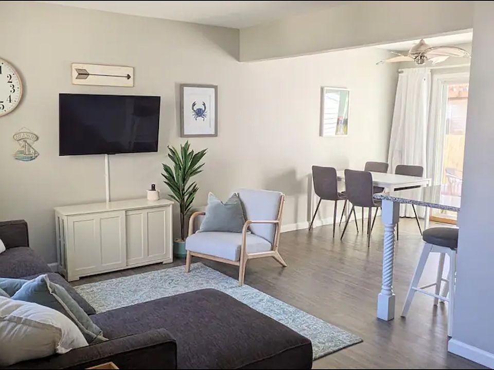 Open concept living, dining and kitchen area with access to a small deck and yard surrounded by a privacy fence.