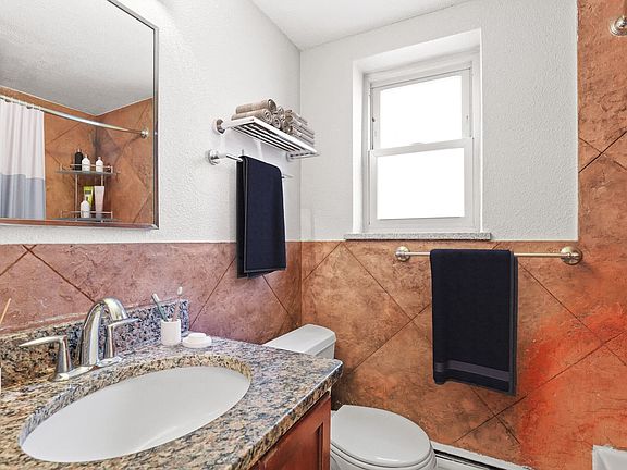 Stylish bathroom with granite vanity and warm tile