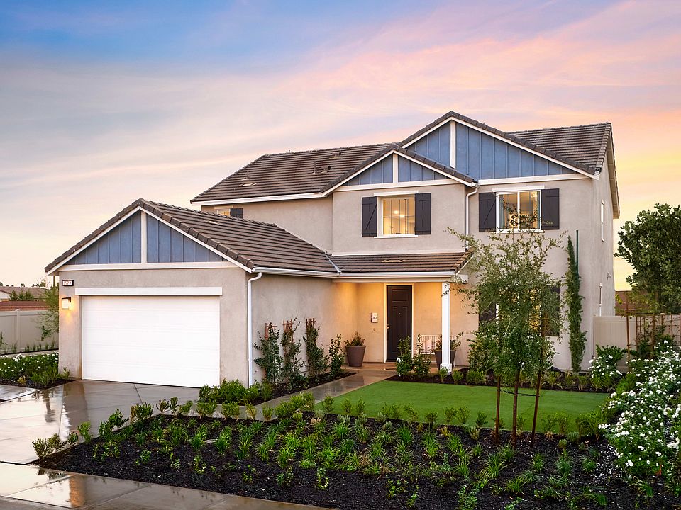 A two-story residential house with a garage, surrounded by a well-manicured lawn and landscaping, se