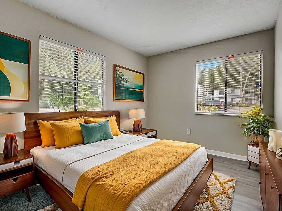Bright and inviting bedroom featuring modern decor, vibrant yellow accents, and large windows with lush outdoor views.