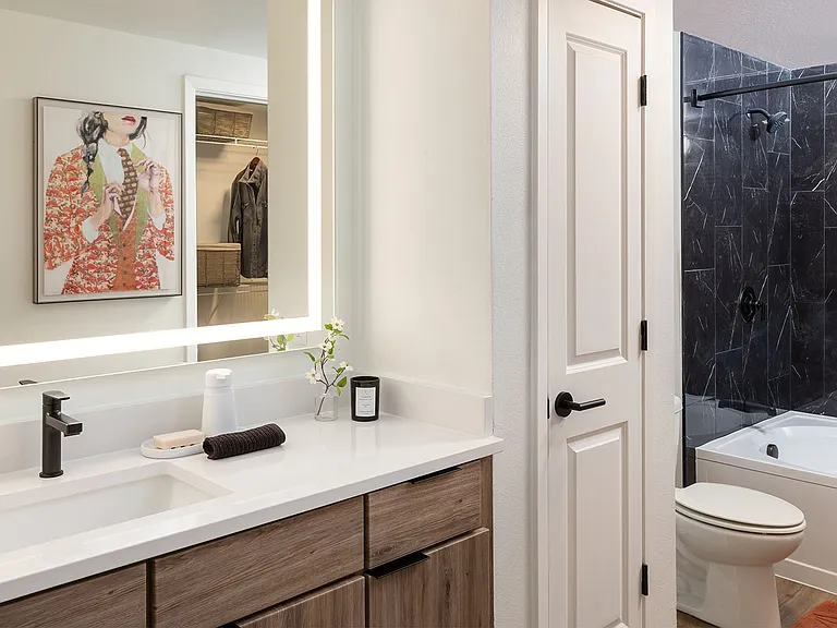 Apartment bathroom with large soaking tub, Tile flooring and LED vanity mirror.