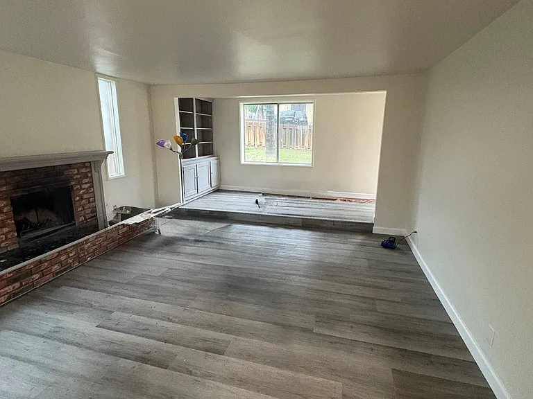 From the kitchen entry, looking back across the living room towards the front window and bookcase in the entry hall