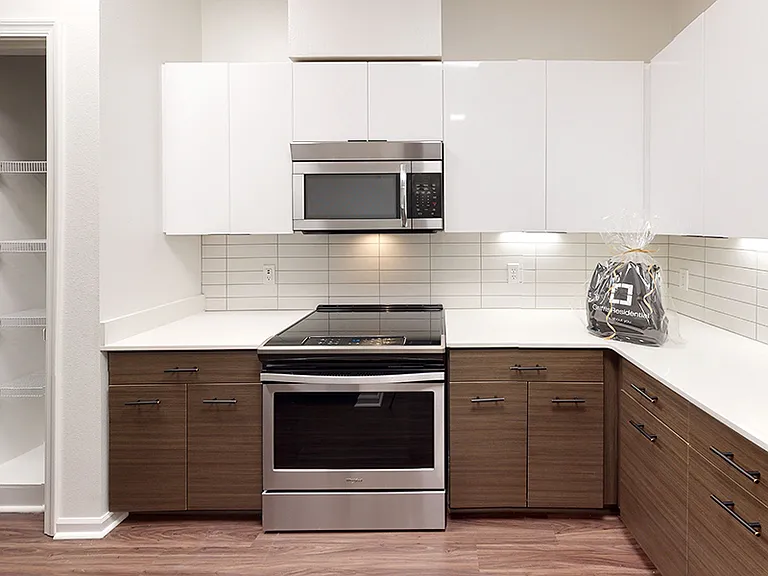 Gourmet kitchen with stainless steel appliances, quartz countertops and wood-style flooring.
