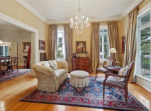 FORMAL LIVING ROOM WITH LOTS OF LIGHT BEAMING THROUGH THE FLOOR TO CEILING WINDOWS. A BEAUTIFUL CRYSTAL CHANDELIER.