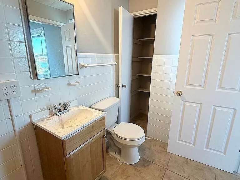 Bright and inviting bathroom featuring modern fixtures, spacious vanity, and convenient open shelving for storage.