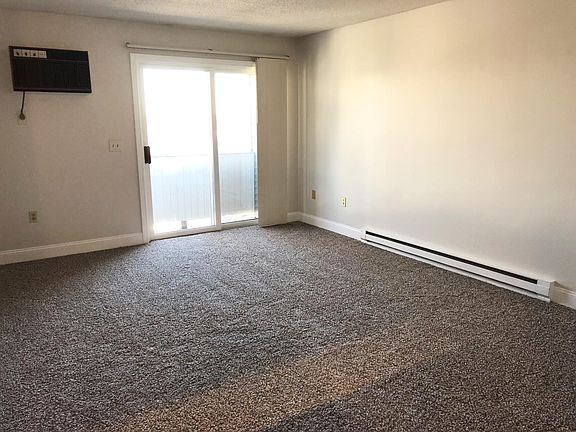 Living room with new carpet, built in AC and sliding doors to private patio