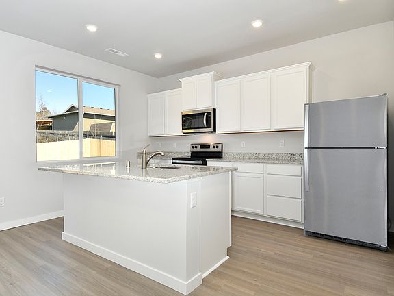 The kitchen has stainless steel appliances and plank flooring.