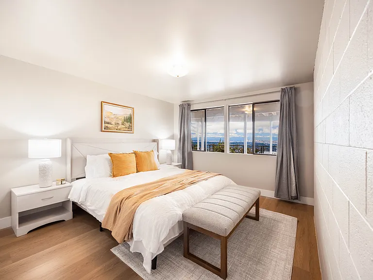 A cozy king bedroom with a plush bed with soft linens, and stylish rattan nightstands.