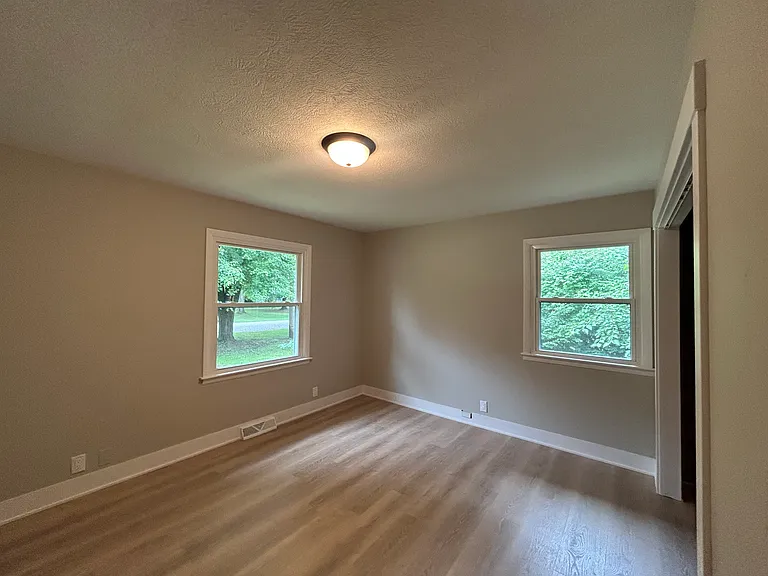 Bedroom with new lighting, windows and vinyl plank flooring.