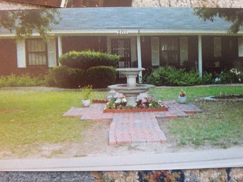 Closer view of house, fountain and flowerbeds