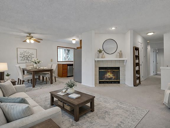 Enjoy a comfortable, sunlit living room with fireplace and open sightlines to the dining area_great for gatherings or quiet evenings at home.