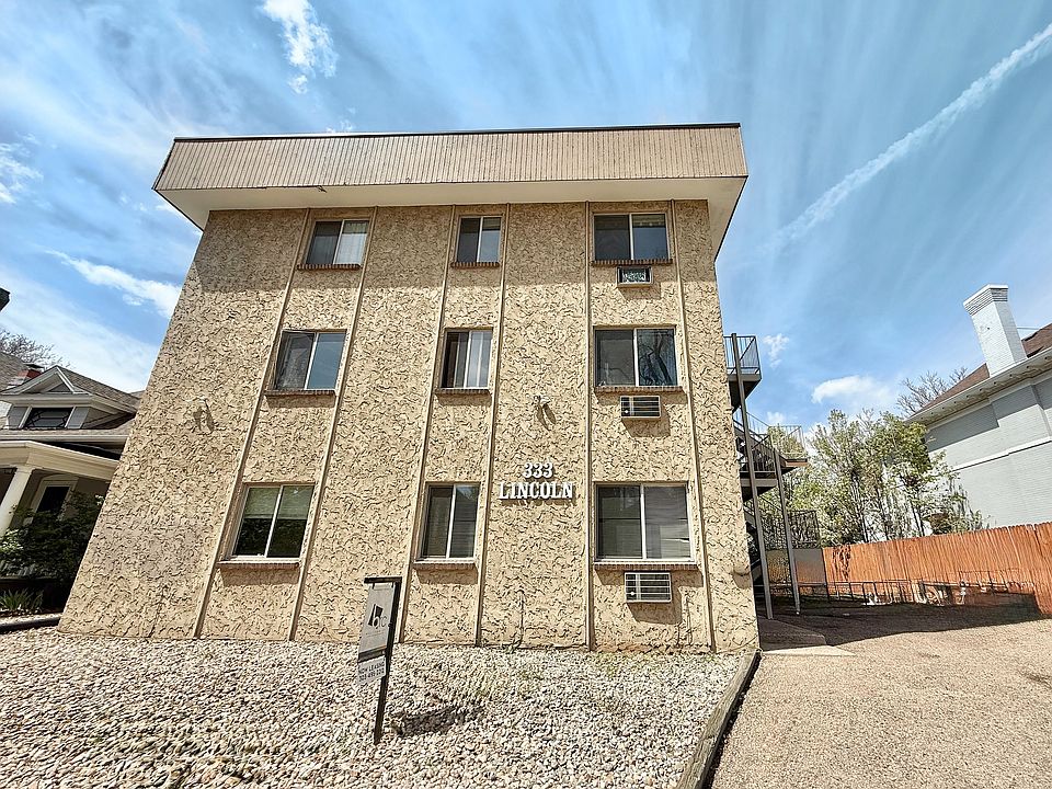 Charming three-story apartment building with unique textured facade and ample windows, located in a serene neighborhood, offering comfortable living spaces.
