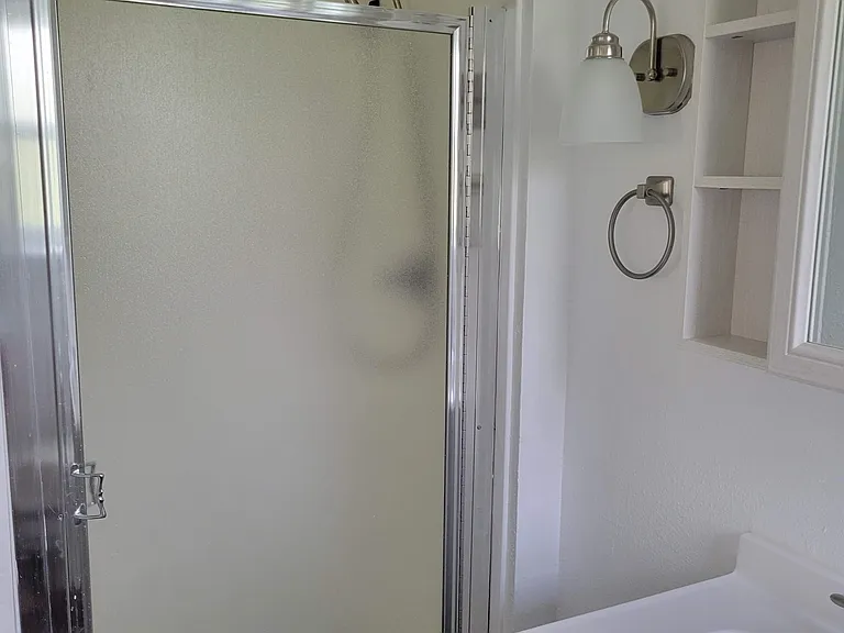 Downstairs shower in ensuite primary bathroom. Unit has 1-year-old hot water heater and high water pressure.