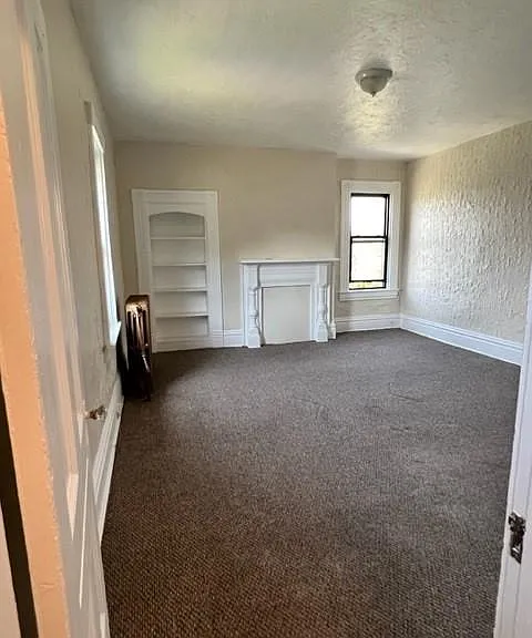 Living Room with a decorative fireplace and built-in bookcase