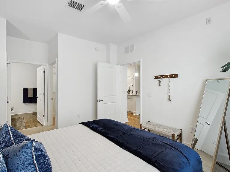 Modern bedroom with elegant decor, featuring a cozy bed, sleek mirror, and stylish accents.