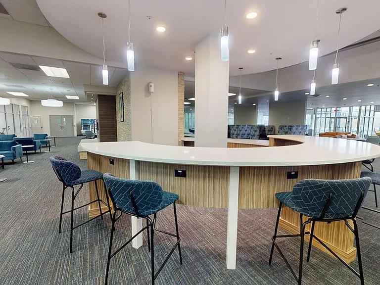 Elegant open-concept lounge area with a modern curved counter, stylish bar stools, and ample seating, perfect for relaxation and social gatherings.