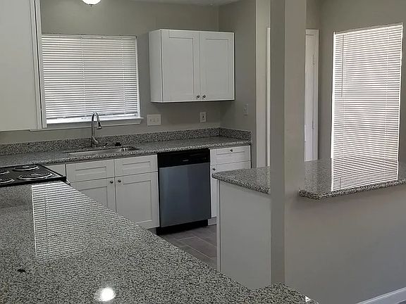 Another view of the kitchen with a view of the pantry, dishwasher. and another counter space covering the same shaker cabinets.
