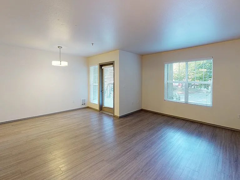 Apartment living room with wood-style flooring and patio or balcony in select homes.