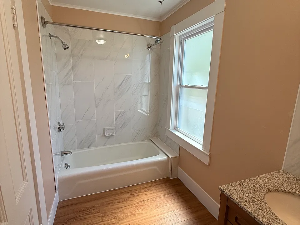 Bright and updated bathroom featuring full tub and marble style tile