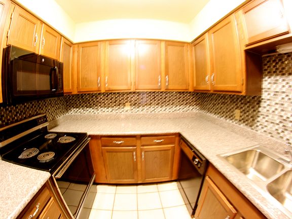 Kitchen with glass tile, granite, black appliances