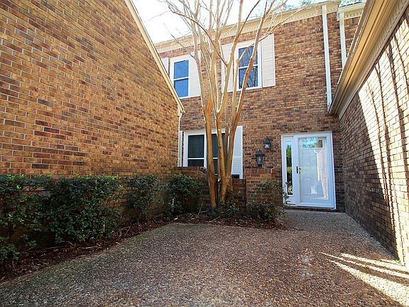 Front door with new entry door, storm door, bushes maintained by HOA, and flowering crepe myrtle