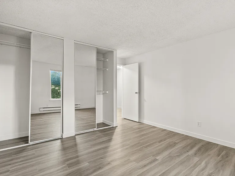 Unwind in a spacious bedroom featuring modern flooring and mirrored closets that enhance both storage and natural light. Unwind in a spacious bedroom featuring modern flooring and mirrored closets that enhance both storage and natural light.