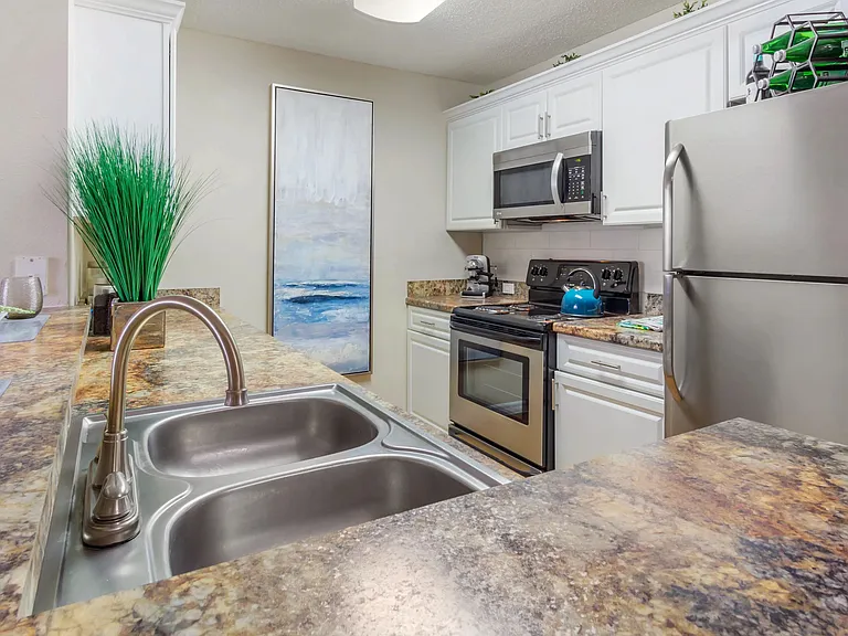 Cook and entertain in style with granite-inspired golden Mascarella countertops, sleek stainless steel appliances, and white cabinetry.