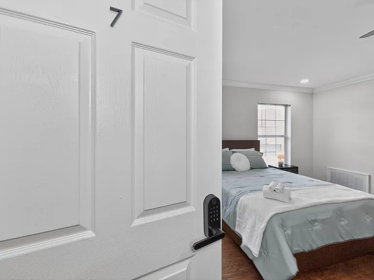 Private bedroom with a full bed, nightstand, and window for natural light, plus a ceiling fan and ample wall space.