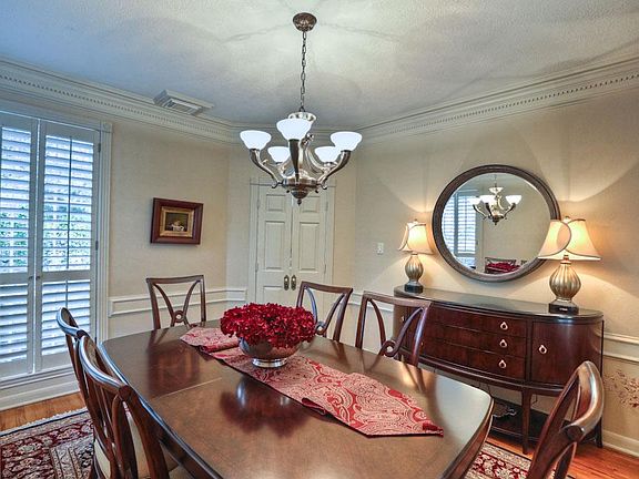 Dining room with art deco lighting and corner windows with plantation shutters.