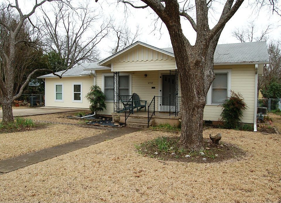 Inviting front porch framed by large pecan trees