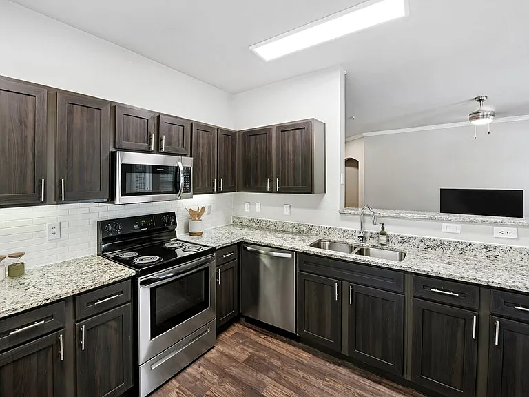 Classic Package II kitchen with stainless steel appliances, espresso cabinetry, white subway tile backsplash, speckled granite countertops, and hard surface flooring