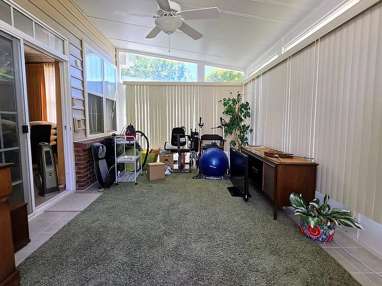 Expansive, bright sunroom complete with a ceiling fan, seamlessly connecting your indoor living space to the backyard area.