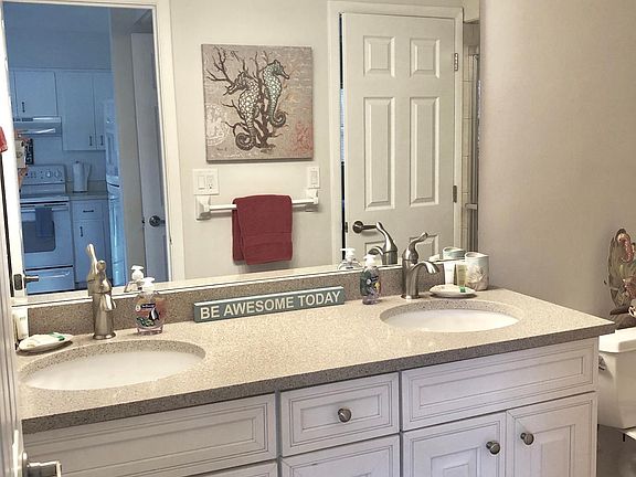 Twin sinks in the full sized bathroom with walk in shower. Cabinets for storing linens. Bright lighting.