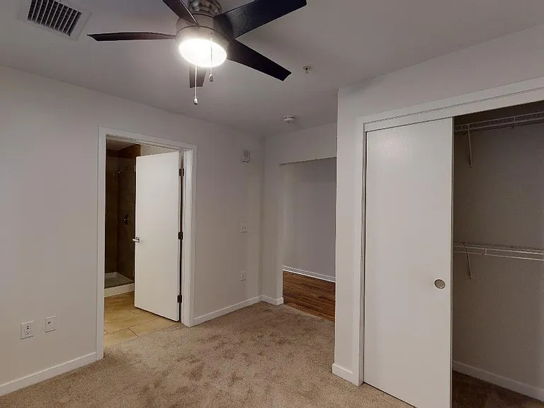 Spacious apartment bedroom with plush carpet flooring.