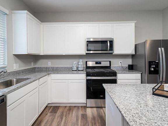 Hardwood floors and a large island in the spacious kitchen make preparing meals. - Model Representat