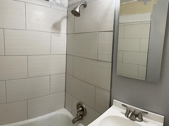 Newly tiled shower and floor, new vanity with sink, toilet and mirrored recessed meanie cabinet