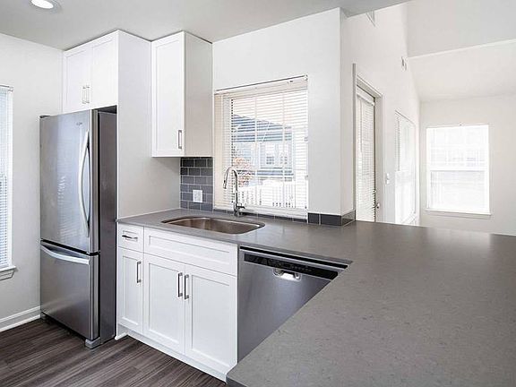 Finish Package II kitchen with gray quartz countertops, tile backsplash, stainless steel appliances, and upgraded fixtures