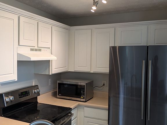 Kitchen featuring stainless steel appliances, modern track lighting, white cabinetry, and high-arc faucet