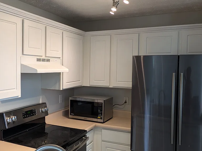 Kitchen featuring stainless steel appliances, modern track lighting, white cabinetry, and high-arc faucet