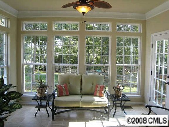 Sunroom with transom windows and new tile flooring overlooking treed backyard.