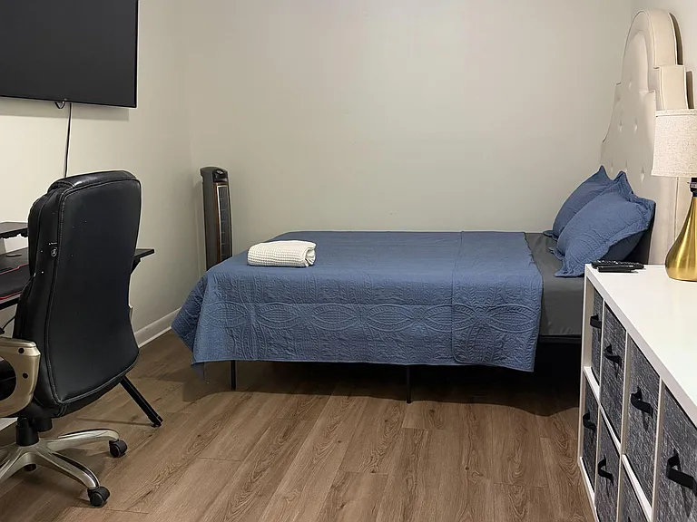 Furnished bedroom with a comfortable bed, dresser storage, and a dedicated desk setup for working or studying.