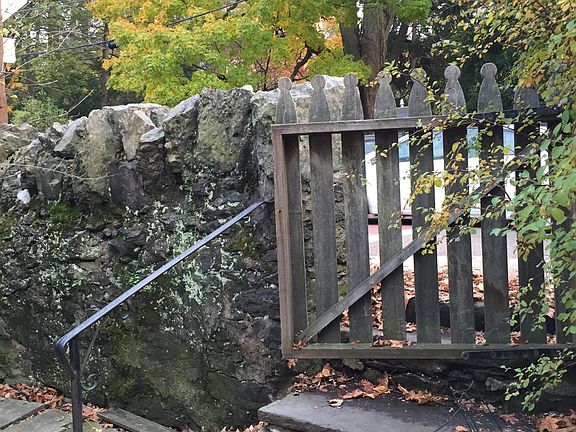 Historic Roxbury Puddingstone wall and wooden gate at the front of the house.